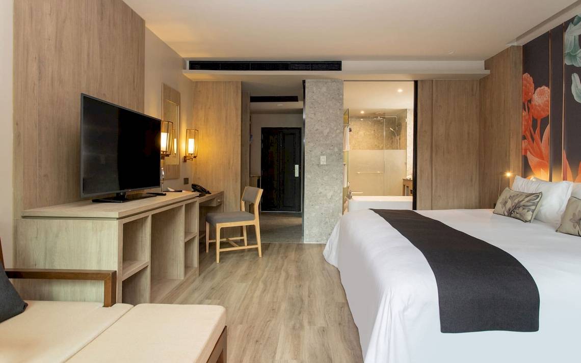 Ein modernes Hotelzimmer mit Fernseher, Schreibtisch und Bett im La Flora Khao Lak Hotel.
