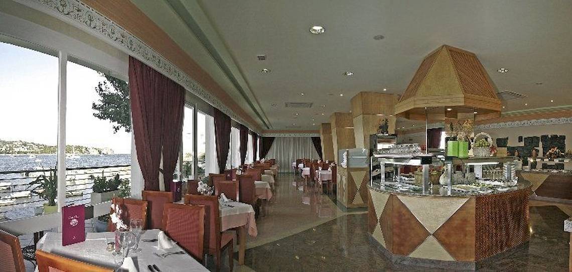 Innenansicht des Restaurants im Argos Hotel mit Blick auf den See und gedeckten Tischen.