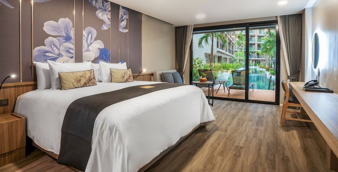 Schlafzimmer im La Flora Khao Lak Hotel mit großem Bett, blauen Blumenmustern an der Wand und Terrassenzugang.