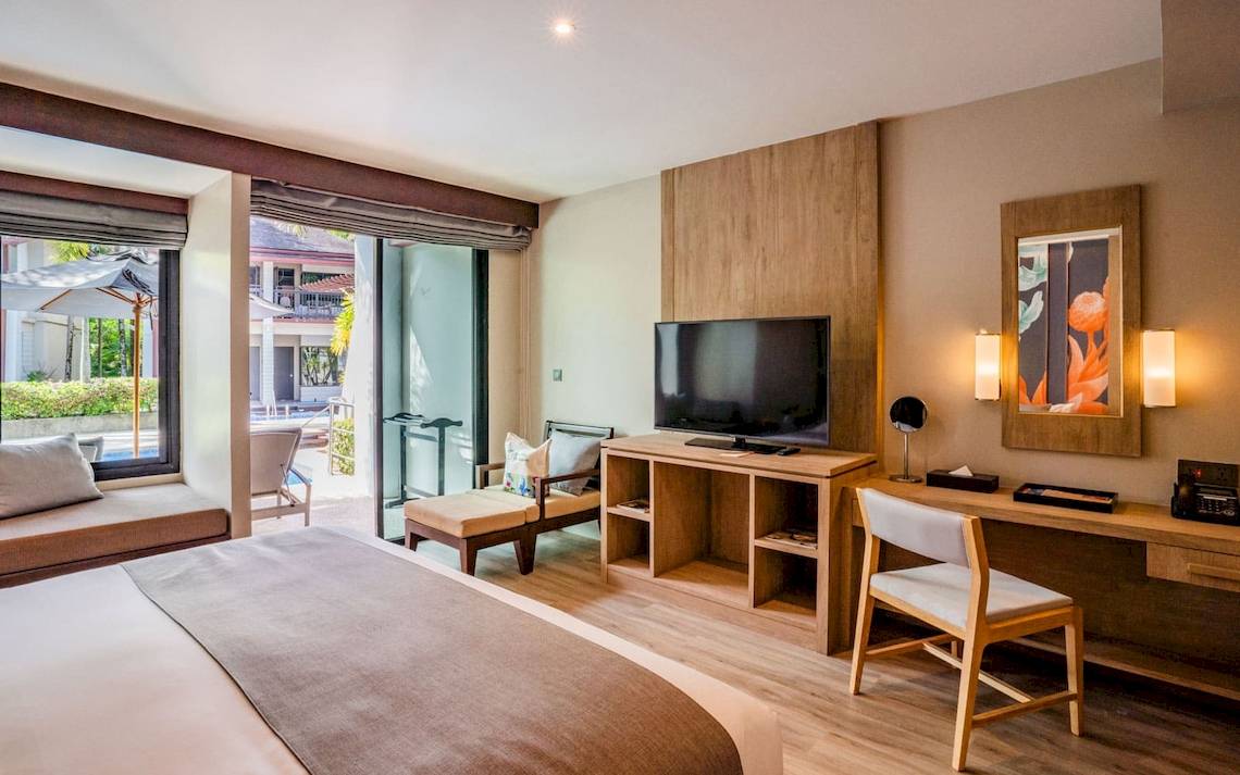 Innenansicht eines Zimmers im La Flora Khao Lak Hotel mit Bett, Fernseher und Schreibtisch.