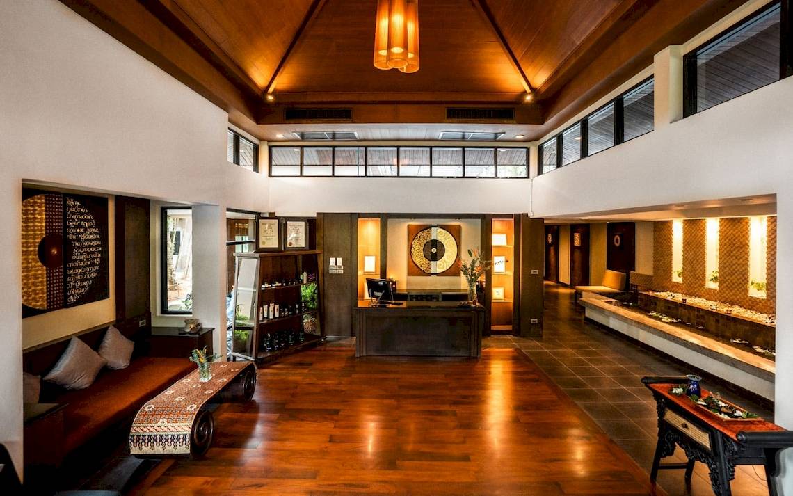 Innenansicht des Eingangsbereichs des La Flora Khao Lak Hotels mit Holzboden und Möbeln.
