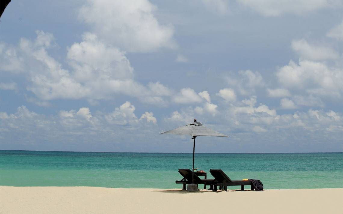 Ein Strand von Bangsak Village mit zwei Liegen und einem Schirm