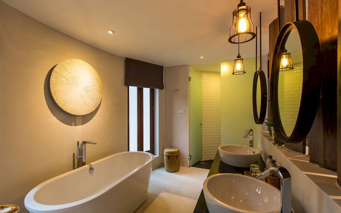 Badezimmer im Bangsak Village Hotel mit Badewanne, Waschbecken und Spiegeln.
