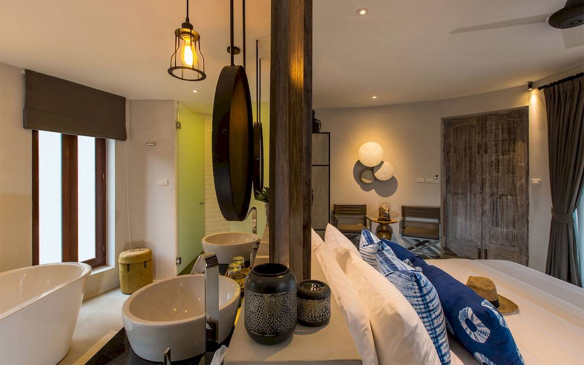 Innenansicht des Schlafzimmers im Bangsak Village Hotel mit Bett, Spiegeln und Deko.