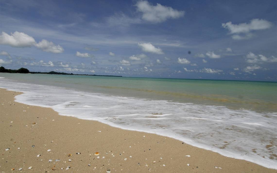 Foto einer Strandlinie mit sanften Wellen und blauem Himmel, bedeckt mit Wolken, vor dem Bangsak Village Hotel