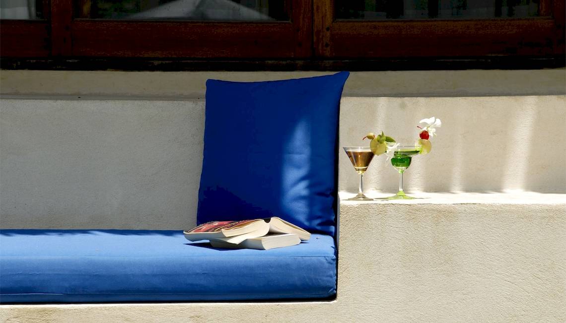 Sofa mit blauem Kissen und zwei Cocktails auf der Bank im Freien.