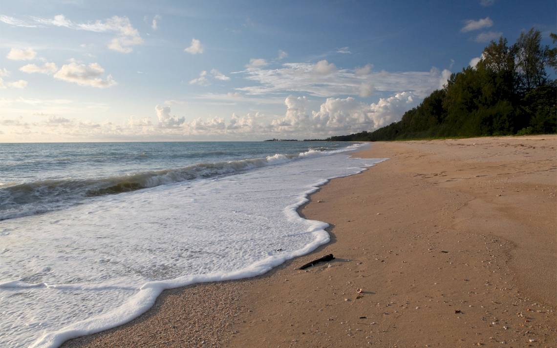 Strand mit sanften Wellen und blauem Himmel mit einigen Wolken