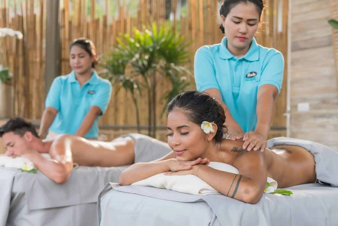 Massage-Behandlung im Treehouse Villas Koh Yao mit zwei Frauen, die Männern Rückenmassagen geben.