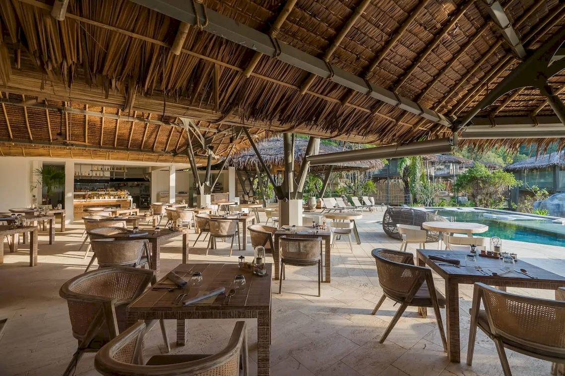 Innenansicht des Restaurants der TreeHouse Villas Koh Yao mit Tischen und Stühlen und Blick auf den Pool.