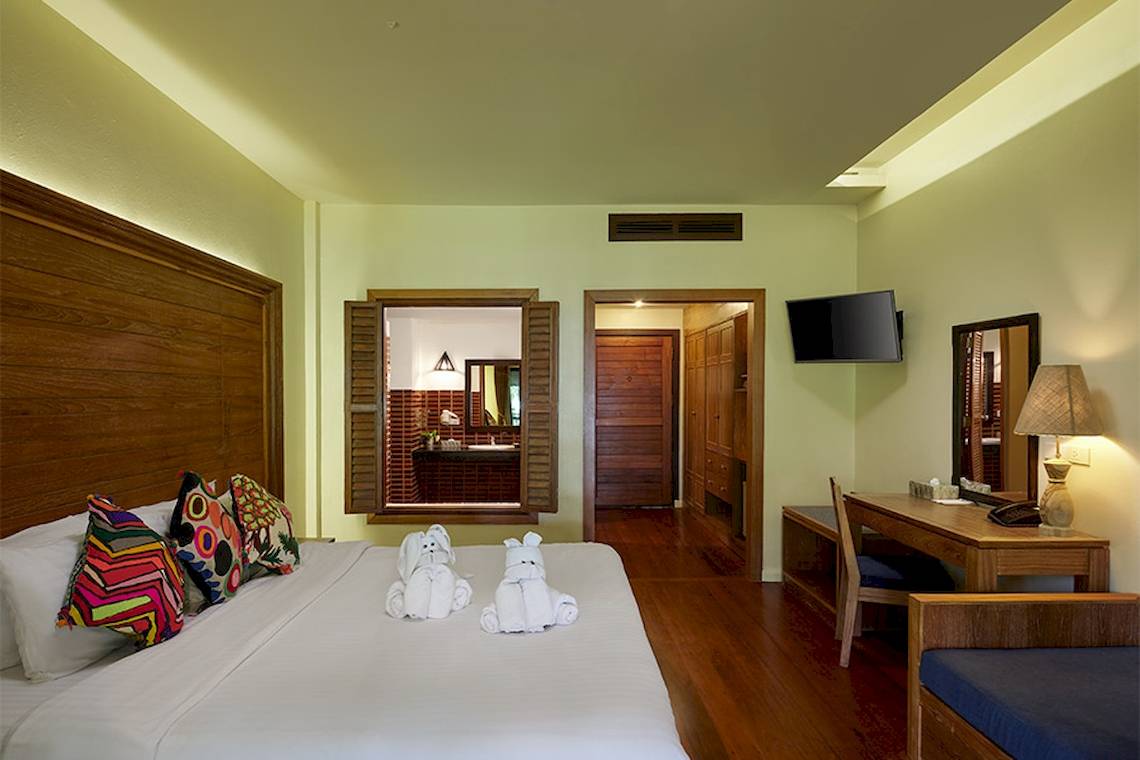 Hotelzimmer im Khaolak Paradise Resort mit zwei weißen Handtüchern auf dem Bett und einem Fernseher an der Wand.