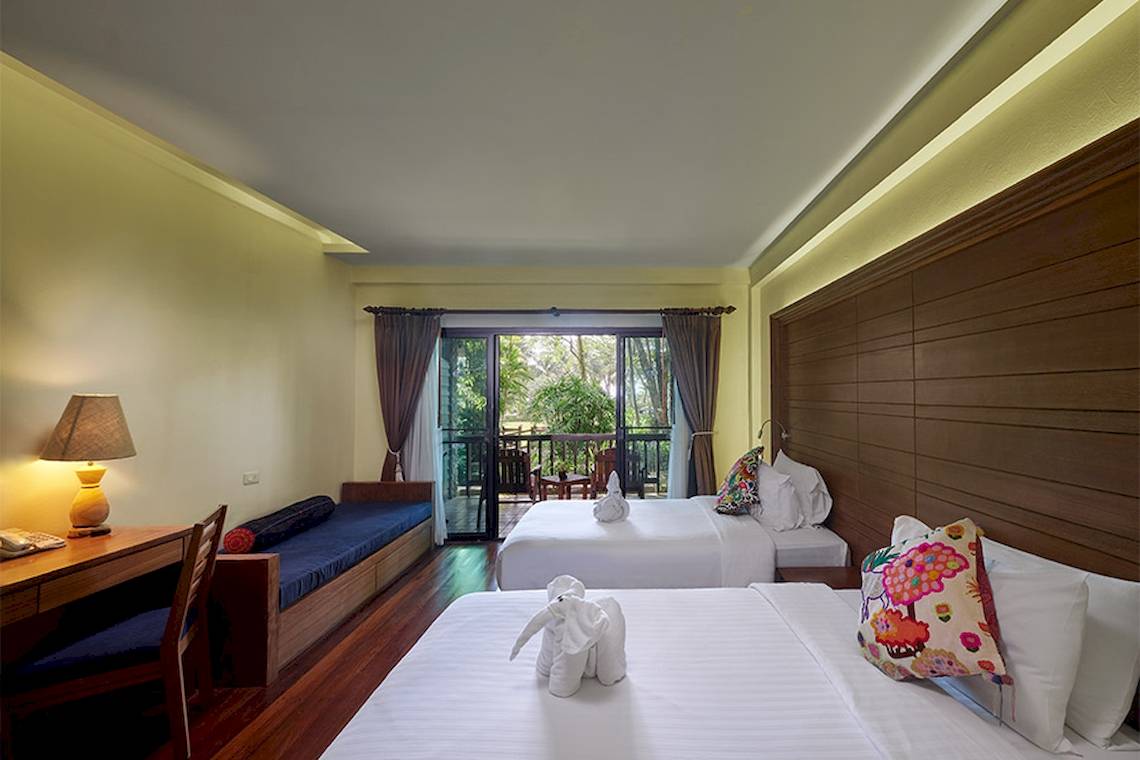 Doppelzimmer im Khaolak Paradise Resort mit zwei Betten, Schreibtisch, Lampe und Balkonzugang.
