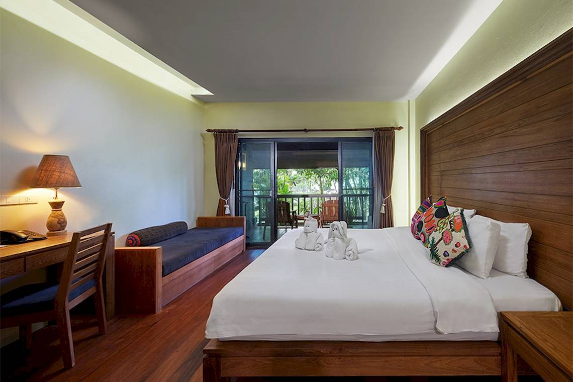 Innenansicht eines Zimmers im Khaolak Paradise Resort mit einem Bett, einem Schreibtisch und einer Veranda.