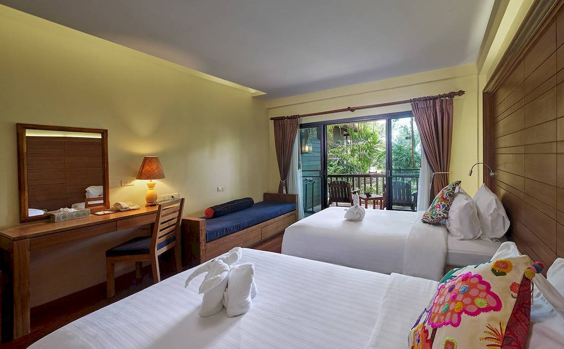 Innenansicht eines Zimmers im Khaolak Paradise Resort mit zwei Betten, Schreibtisch und Balkon.