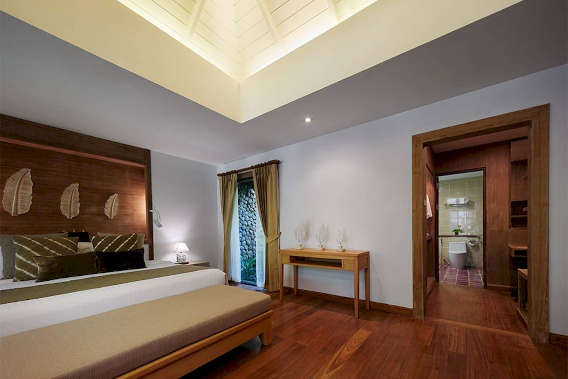 Ein modernes Schlafzimmer im Khaolak Paradise Resort mit Holzboden, einer großen Bett und einem offenen Badezimmer.