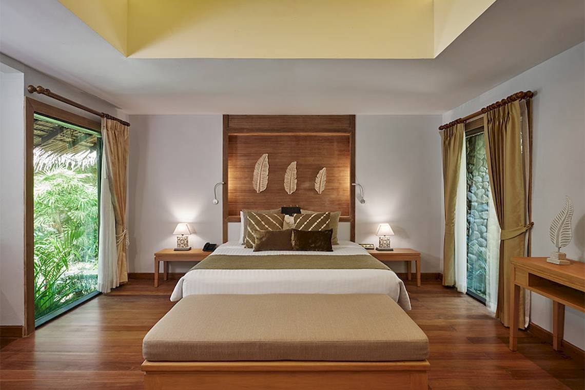 Innenansicht eines Zimmers im Khaolak Paradise Resort mit Doppelbett, Nachttischen und Fenstern.