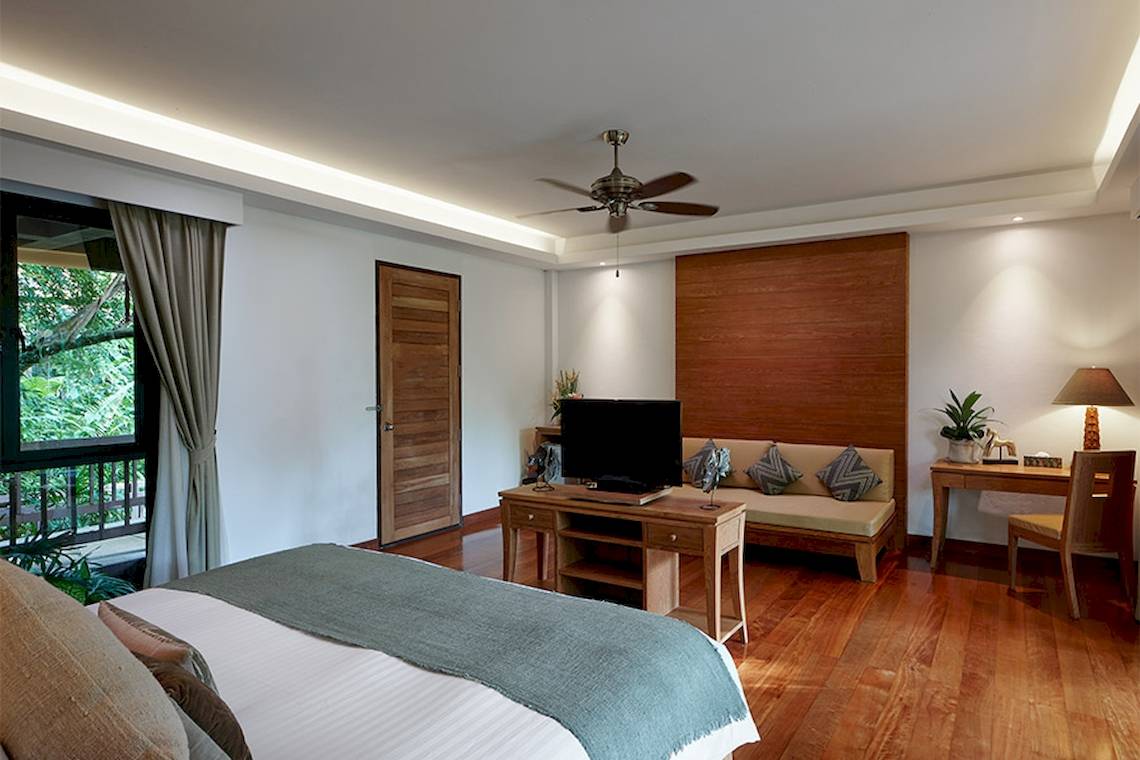 Innenansicht des Schlafzimmers im Khaolak Paradise Resort mit Doppelbett, Schreibtisch, Couch und Fernseher.