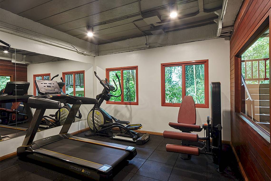Fitnessraum im Khaolak Paradise Resort mit Laufband, Rudergerät und Fenstern.