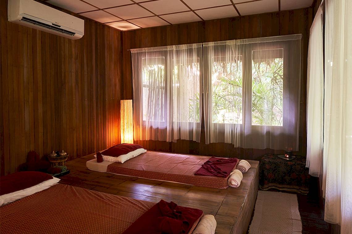 Zwei Betten im Zimmer mit Holzwänden und Fenstern, beide mit roten Decken und Kissen.