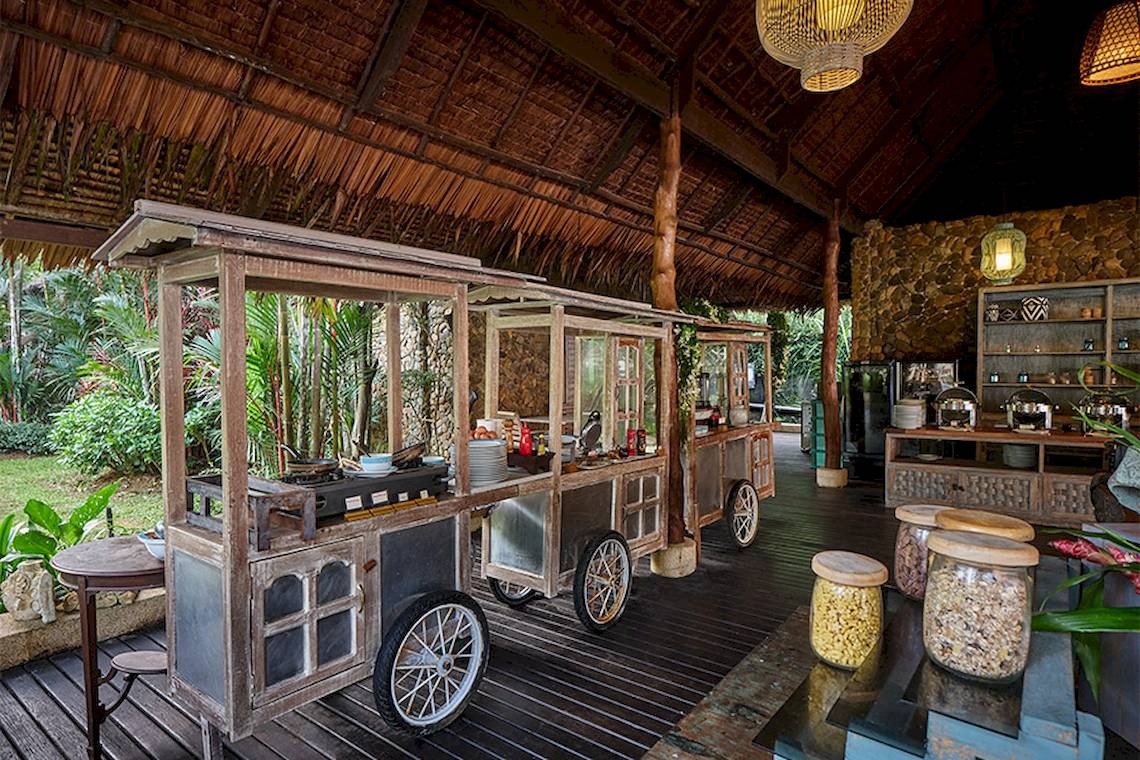 Außenbereich des Khaolak Paradise Resorts mit traditionellem Essenswagen und Holzmöbeln.