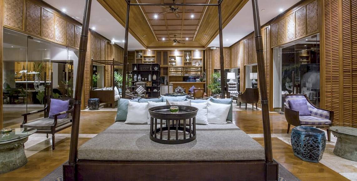 Innenbereich des Santiburi Koh Samui Hotels mit einem großen Bett, Kissen, einem Tisch und Möbeln.