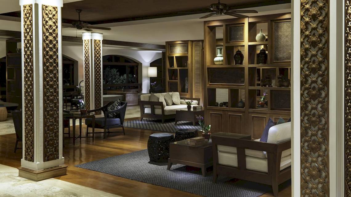 Lobby des Santiburi Koh Samui Hotels mit Holzmöbeln, Sofas, Holzsäulen und Deckenventilatoren.