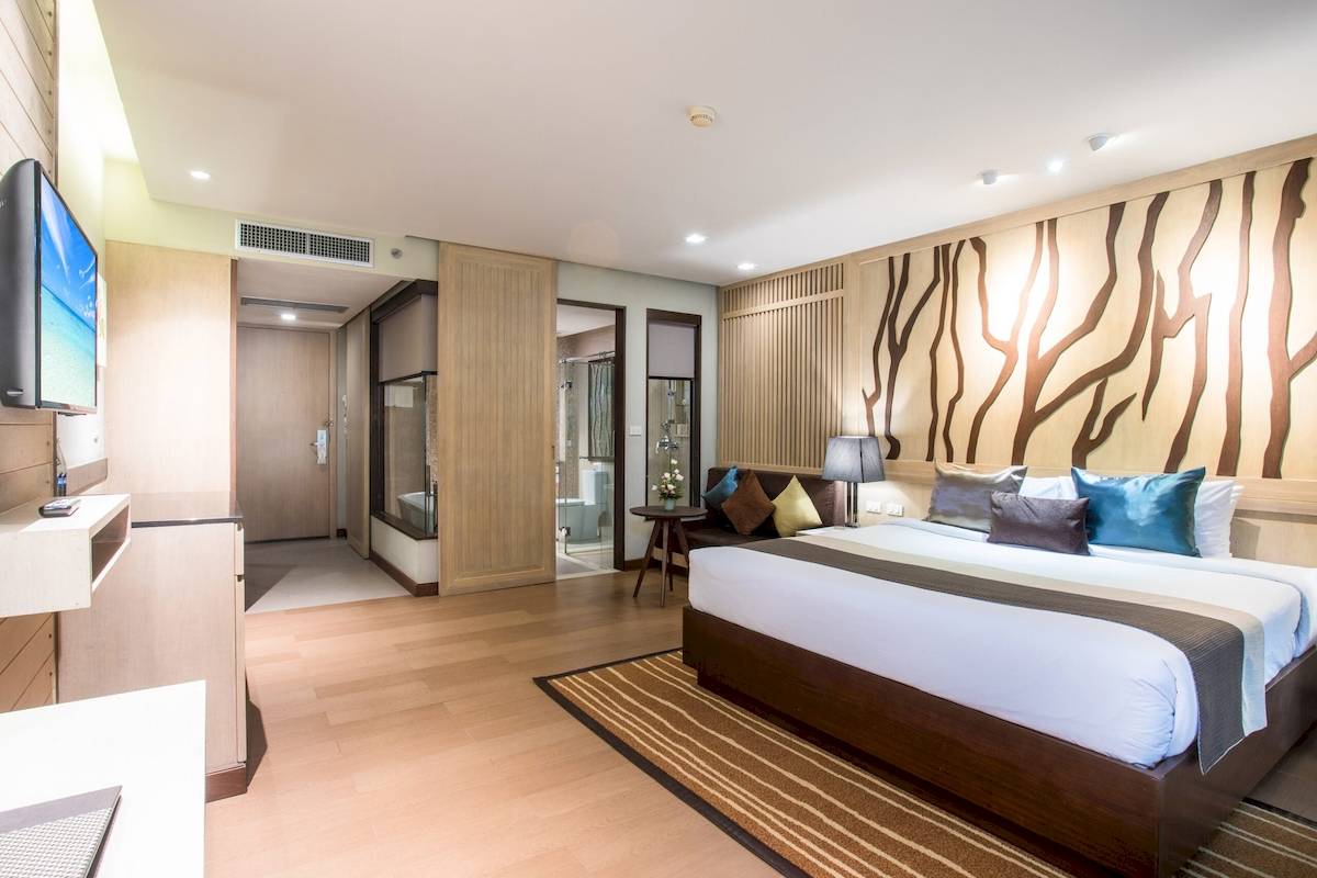 Hotelzimmer im Khao Lak Merlin Resort mit Kingsize-Bett, Fernseher und modernem Interieur.
