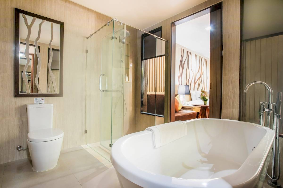 Badezimmer im Khao Lak Merlin Resort mit Badewanne, Dusche und Spiegel.