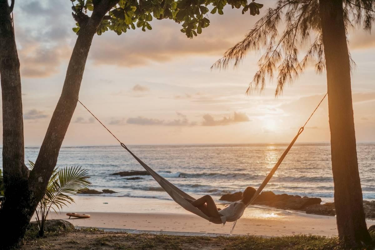 Frau auf einer Hängematte am Strand bei Sonnenuntergang, Khao Lak Merlin Resort