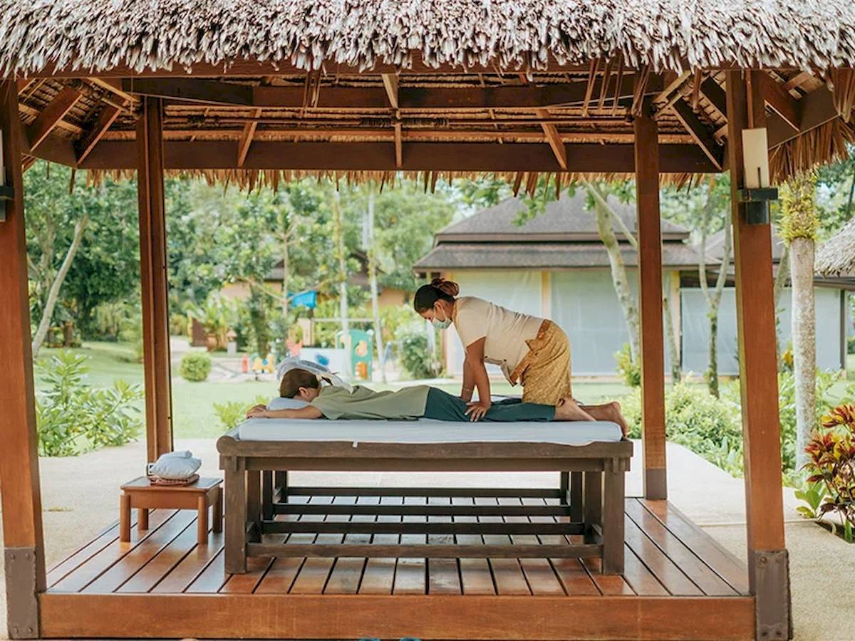 Massage im Pavillon im Khao Lak Merlin Resort mit einer Frau, die einen Mann massiert.