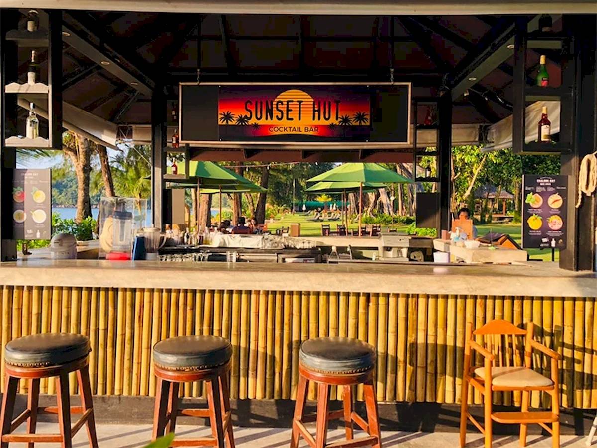 Cocktailbar im Khao Lak Merlin Resort mit Sonnenuntergangs-Thema und grünen Sonnenschirmen.