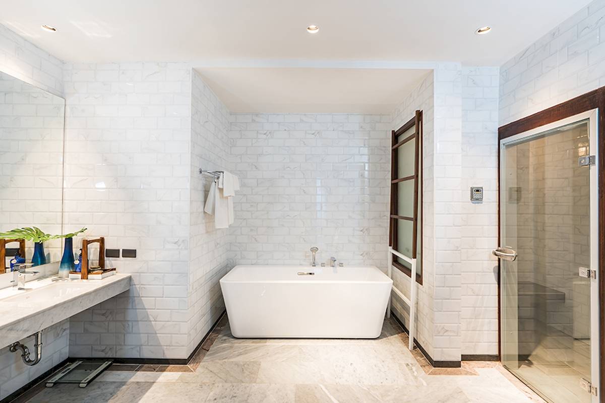 Innenansicht eines Badezimmers im Peace Resort mit weißen Fliesen, einer Badewanne und einem Spiegel.