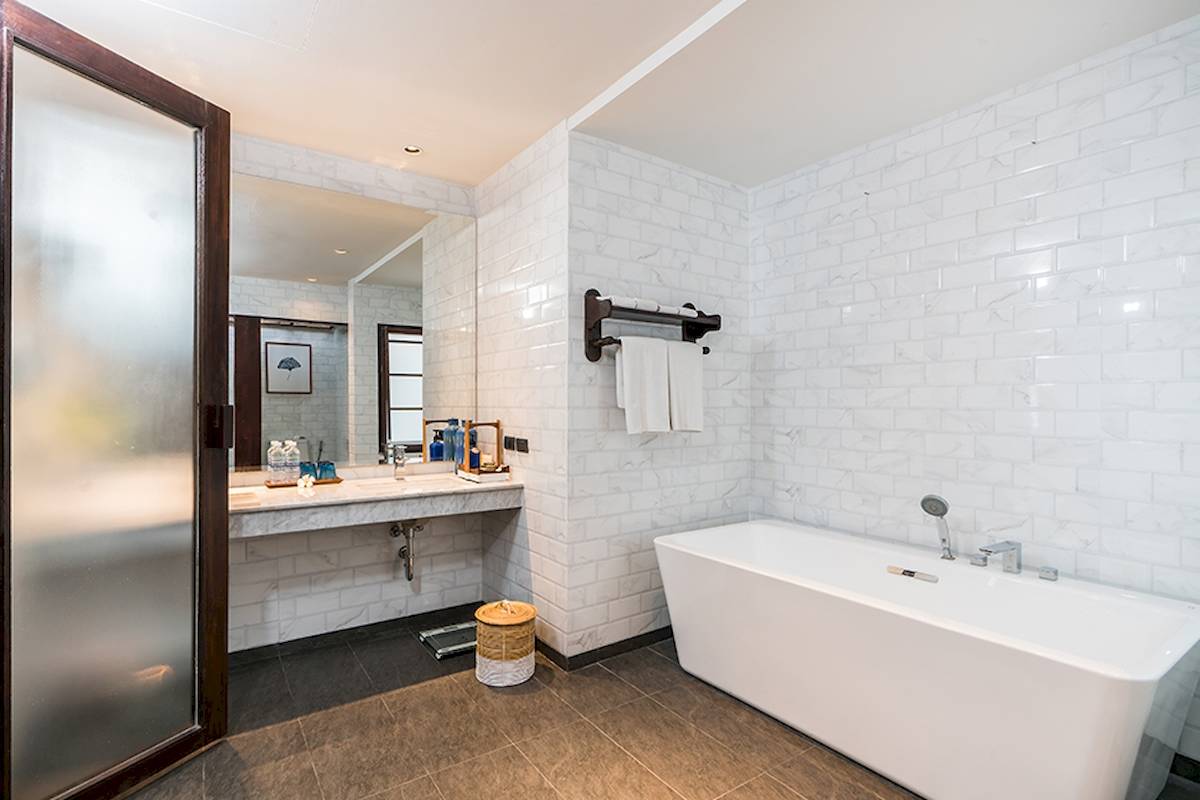 Badezimmer im Peace Resort mit weißen Fliesen, Badewanne und Waschbecken.