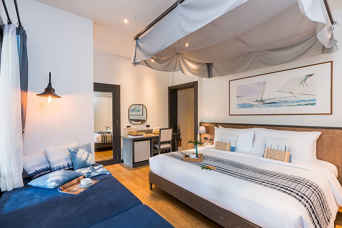 Schlafzimmer im Peace Resort mit zwei Betten, Nachttischen, Lampe und Gemälde an der Wand.