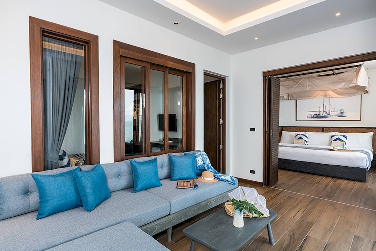 Wohnzimmer der Ferienwohnung in Friedrichshafen mit Sofa, Tisch und offenem Schlafzimmer.