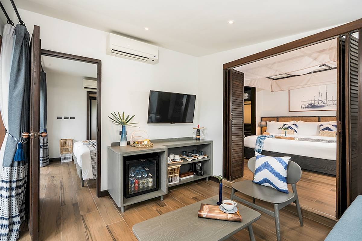 Innenansicht eines Zimmers im Peace Resort mit modernem Dekor, Fernseher, Minibar und offenem Schlafzimmer.