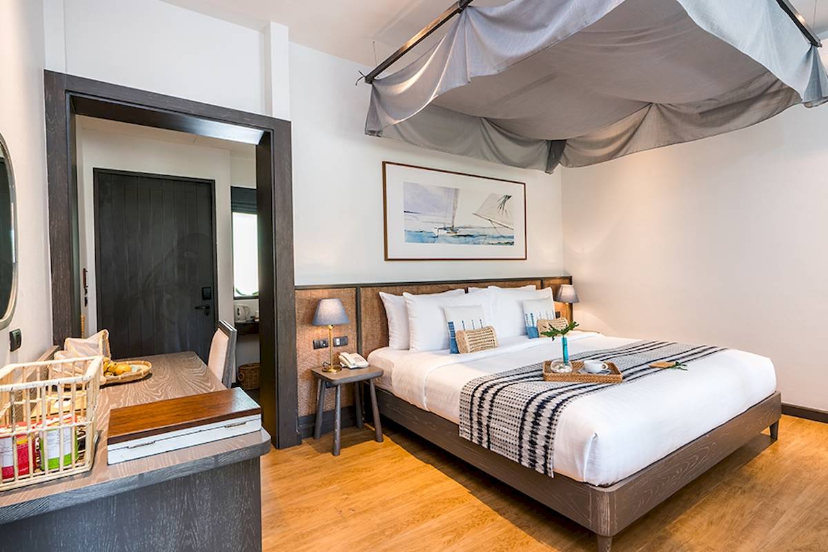 Schlafzimmer im Peace Resort mit Doppelbett, Nachttischen, Lampen und Gemälde an der Wand.