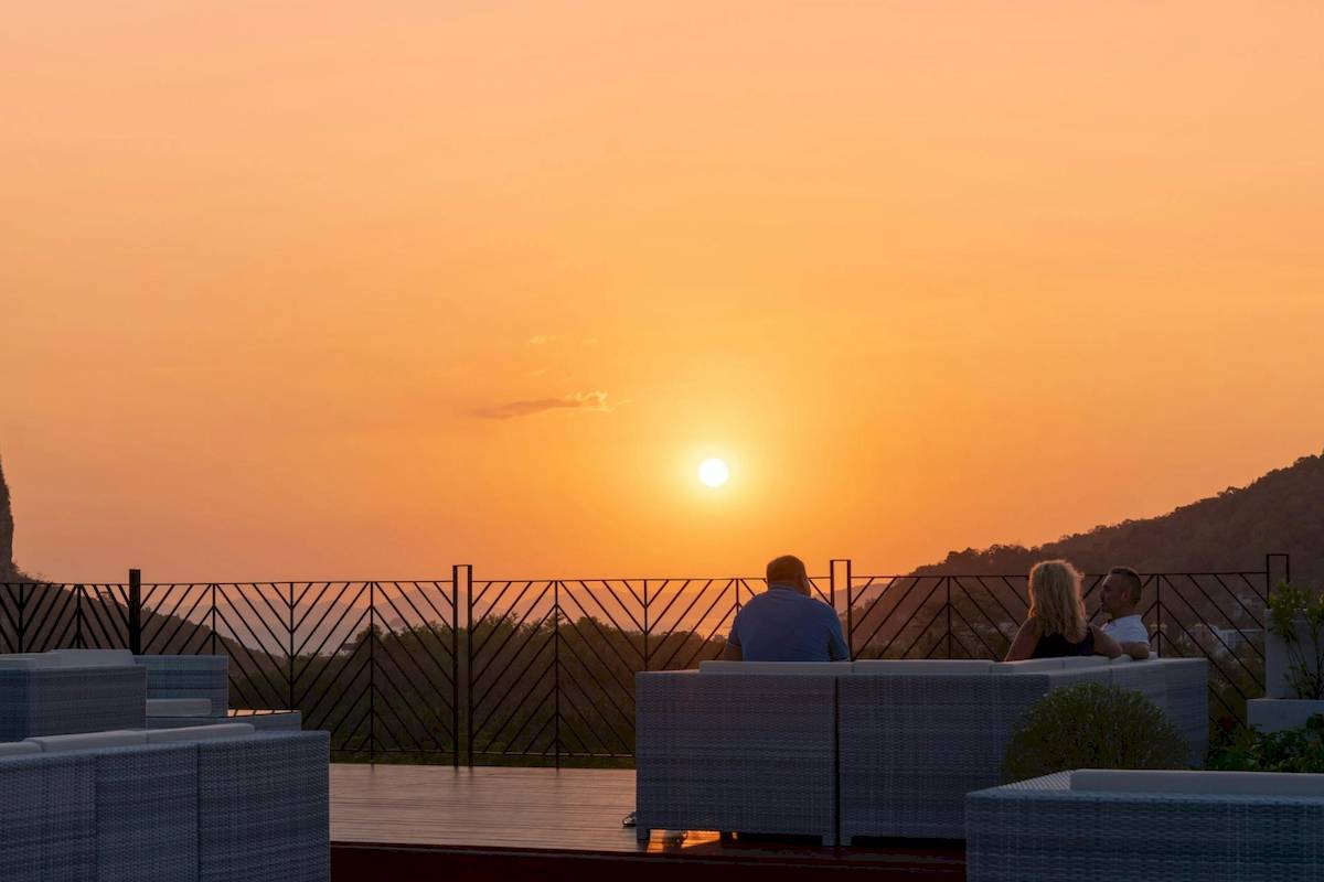 Drei Personen auf der Terrasse des Anana Ecological Resort Krabi bei Sonnenuntergang.