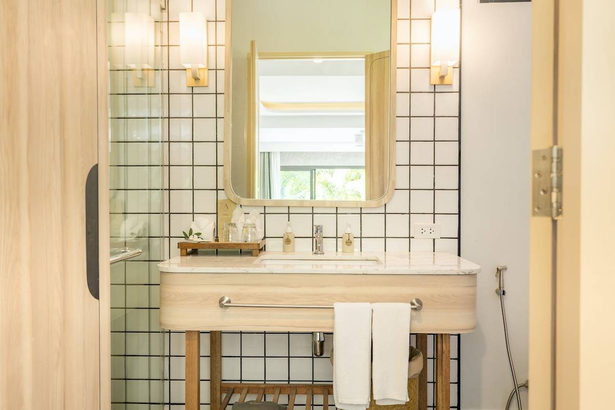 Badezimmer im Anana Ecological Resort Krabi mit Marmorwaschbecken, Spiegel und weißen Kacheln.