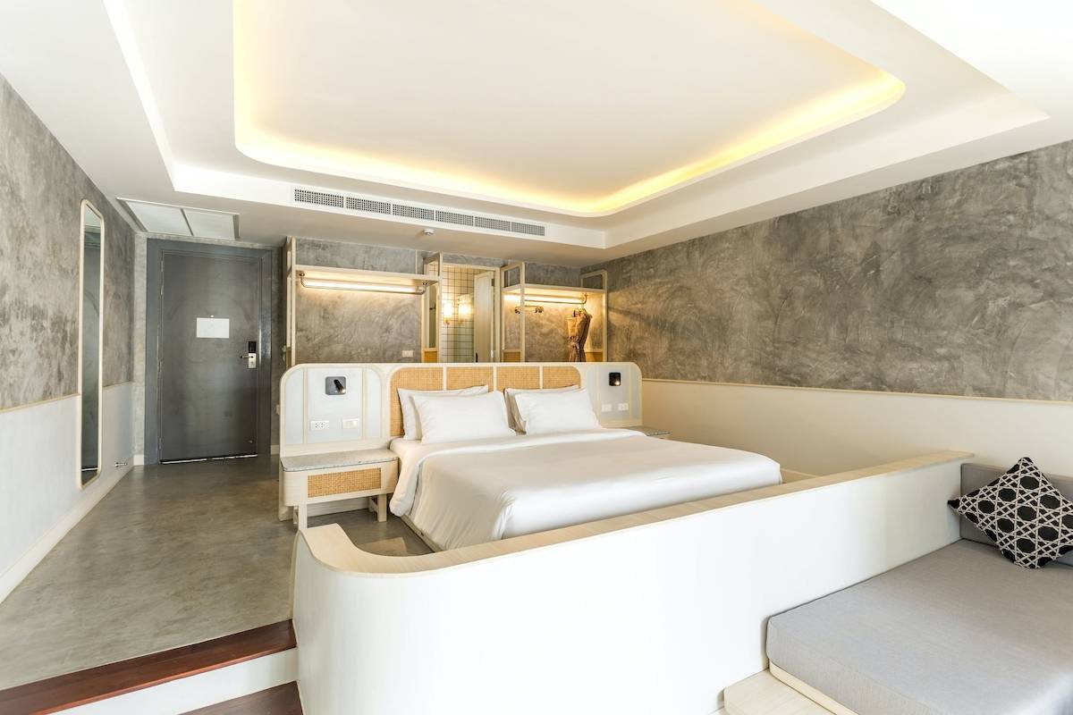 Innenansicht eines Zimmers im Anana Ecological Resort Krabi mit einem großen Bett, grauen Wänden und modernen Möbeln.