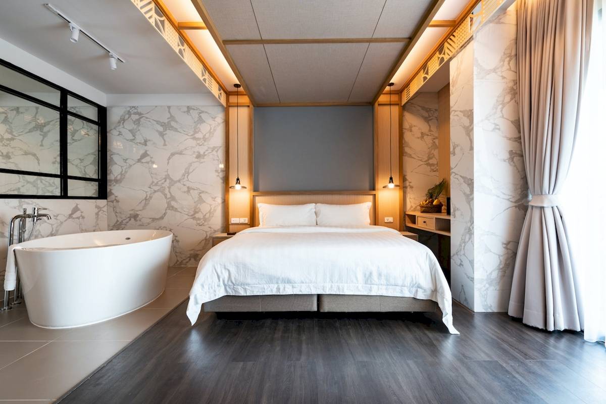 Schlafzimmer im Anana Ecological Resort Krabi mit Doppelbett, Badewanne und Marmorwänden.