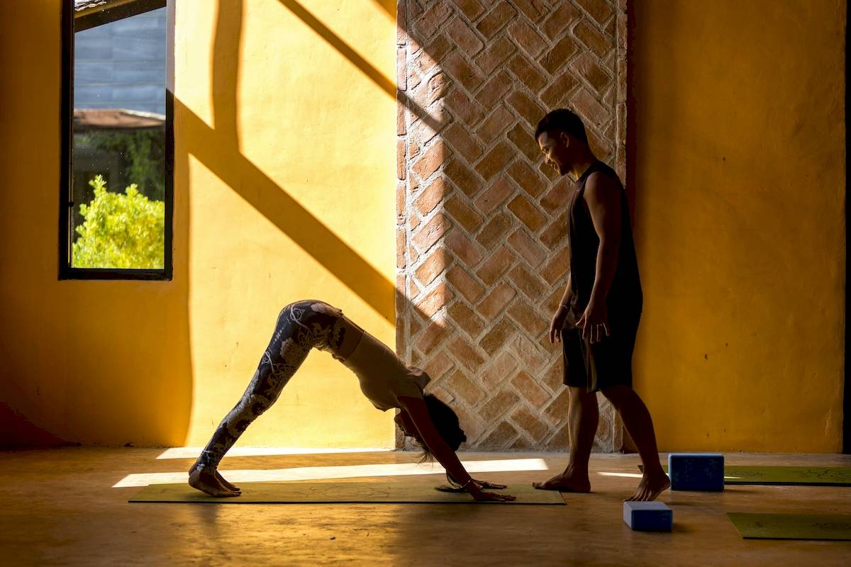 Yoga-Übungen im Anana Ecological Resort Krabi mit einer Frau in einer Dehnungsposition und einem Mann, der zuschaut.
