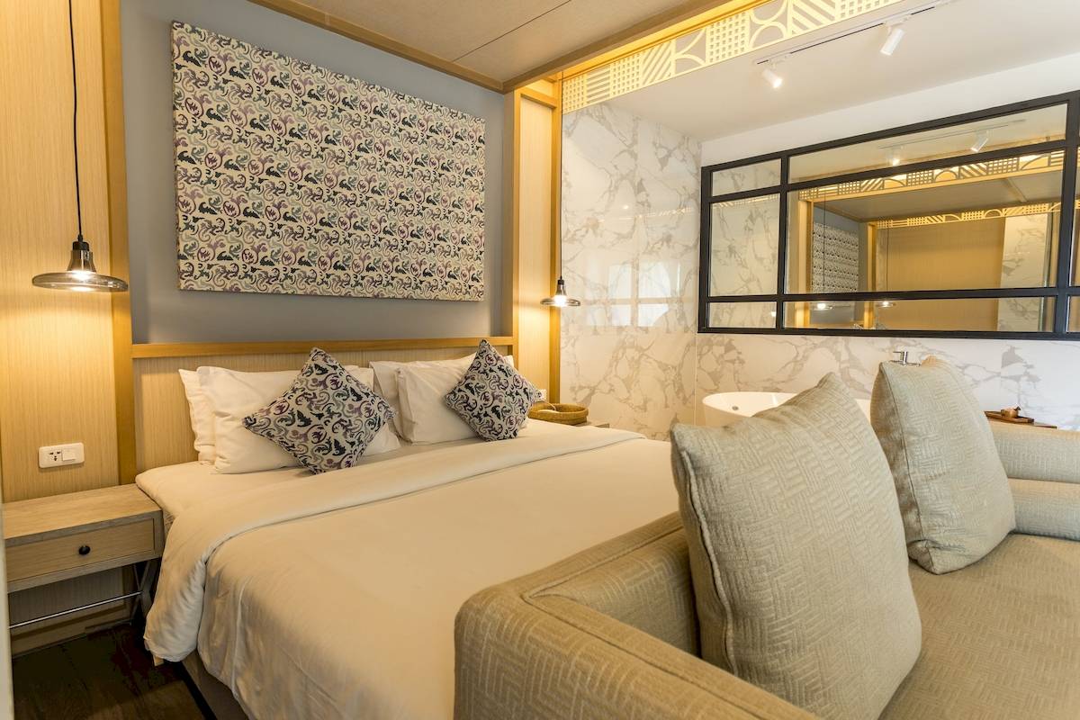 Hotelzimmer im Anana Ecological Resort Krabi mit großem Bett, Sofa, Dekor und Badezimmerspiegel.