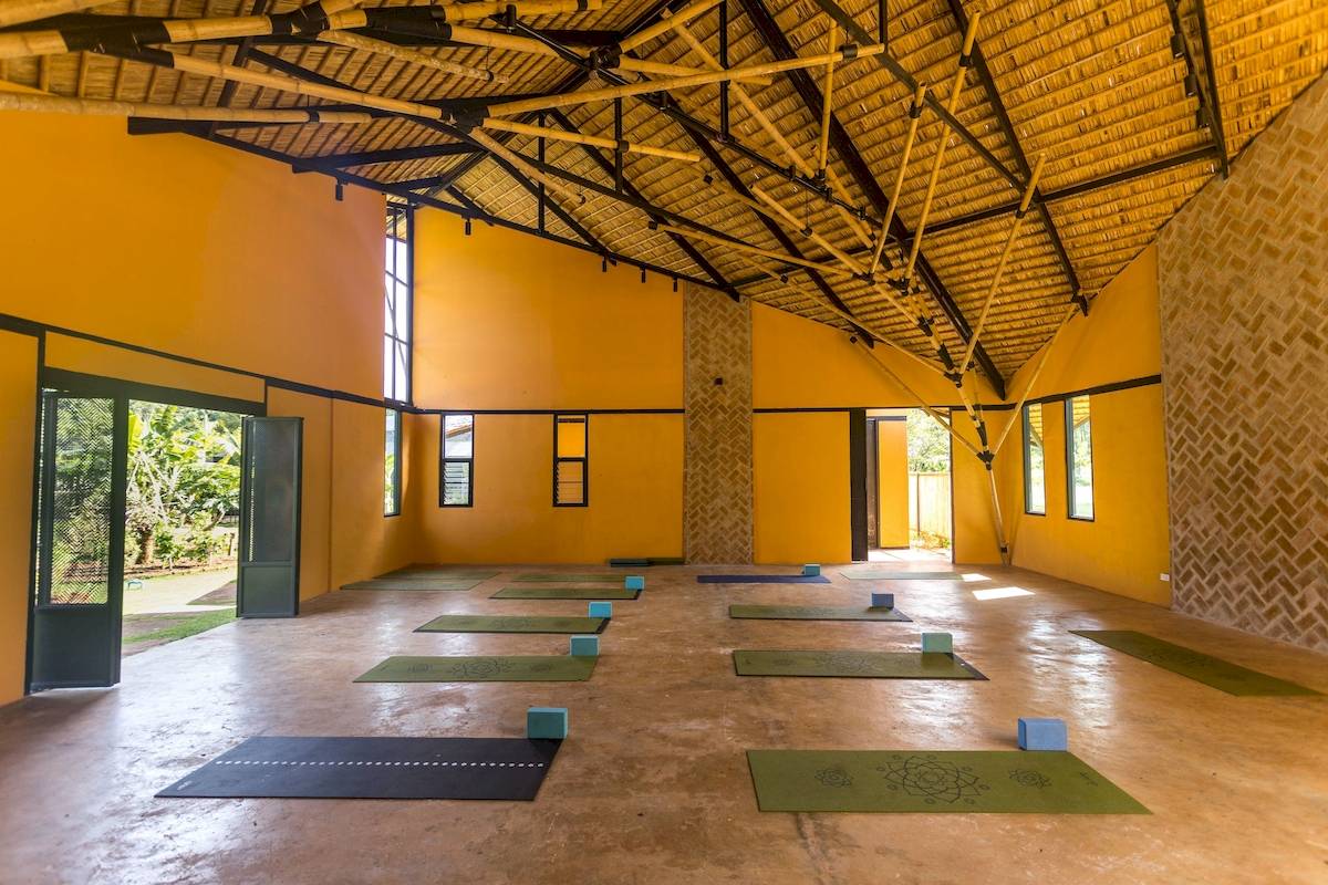 Yogaraum im Anana Ecological Resort Krabi mit gelben Wänden und Bambusdach.