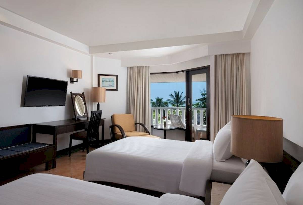 Zimmer im Aonang Villa Resort mit zwei Betten, Balkon und Aussicht auf Palmen und Meer.