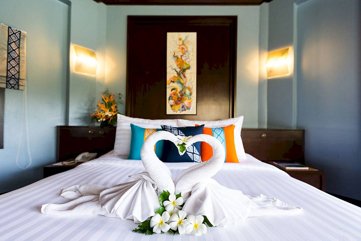 Ein Bett mit einem Schwanen-Arrangement aus Handtüchern und Blumen im Peace Laguna Resort & Spa.