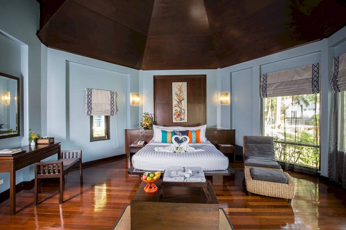 Ein elegantes Hotelzimmer im Peace Laguna Resort & Spa mit einem großen Bett, Holzboden und modernen Möbeln.