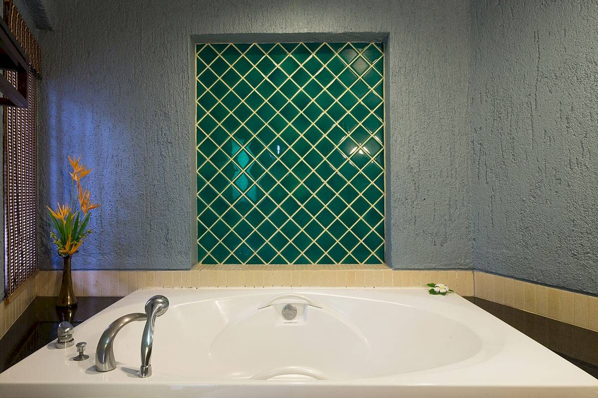 Badezimmer mit großer Badewanne und Blumenvase im Peace Laguna Resort & Spa