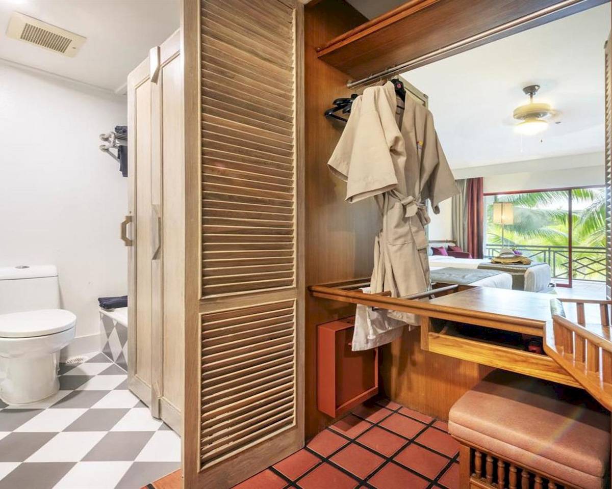 Hotelzimmer im Chada Thai Village Resort mit Blick auf einen Balkon und tropischen Pflanzen.