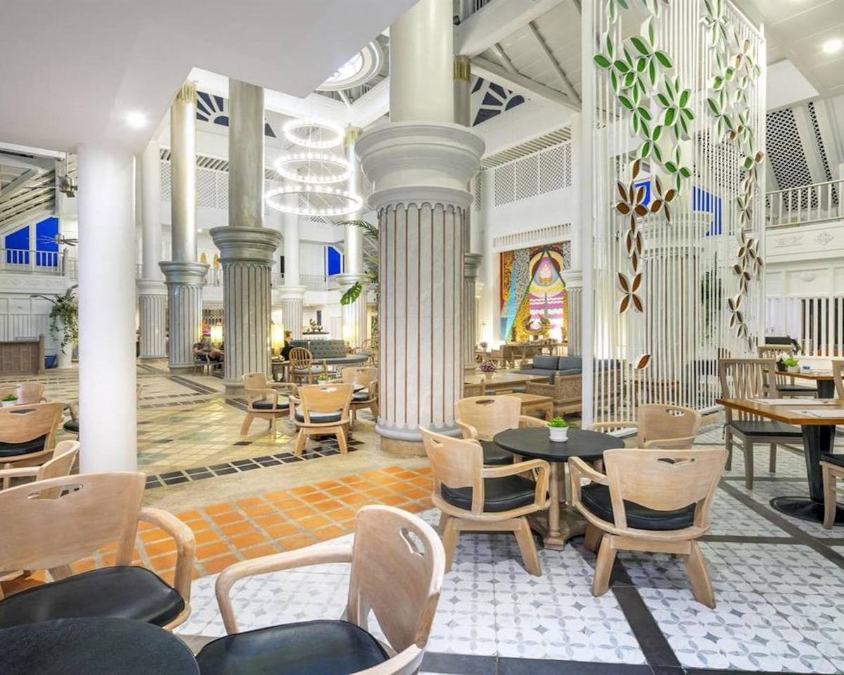 Interieur des Chada Thai Village Resorts mit Säulen, Tischen und Stühlen.