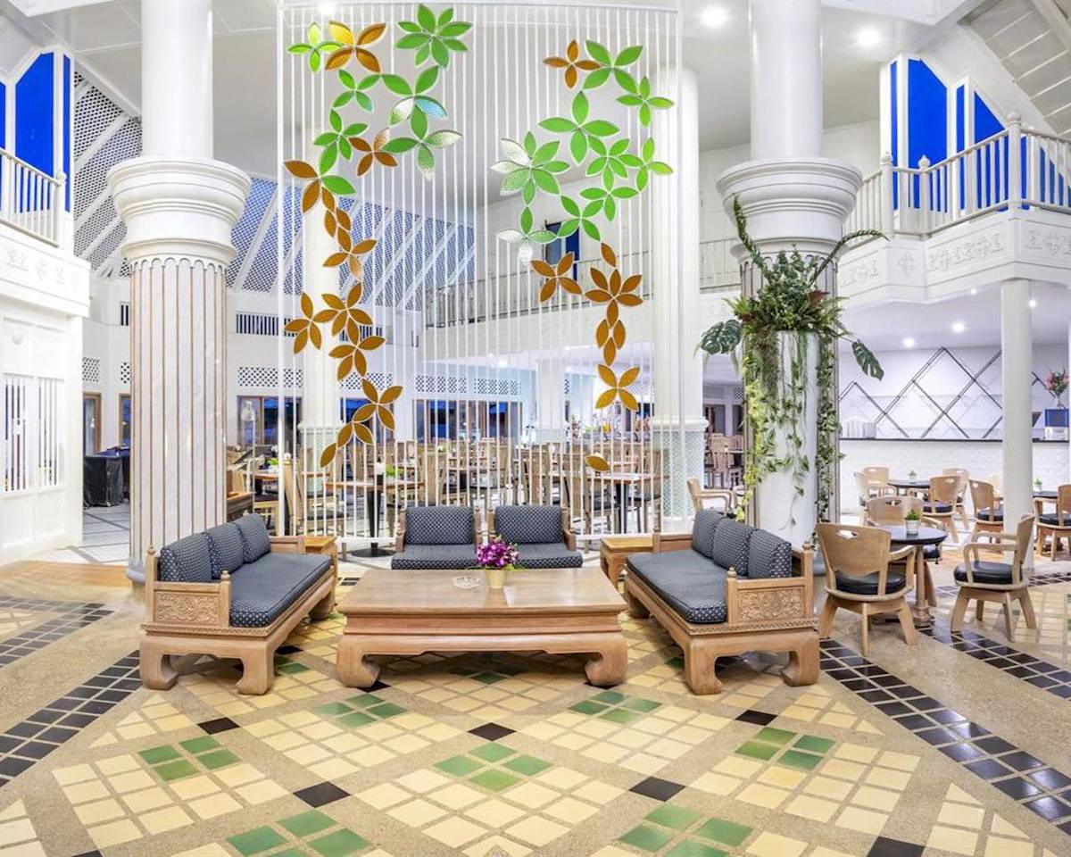 Hotellobbybereich mit Sofas, Tischen, dekorativen Wandschirmen und gefliestem Boden.